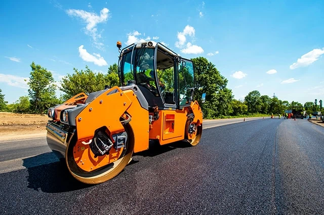 a pavement roller smoothing out a newly constructed road.
