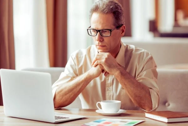 thinking retirement over laptop coffee 1200